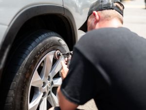 Majeski Wheel Restoration technician sanding and prepping a Lexus alloy wheel for repair on-site in Alexandria, VA